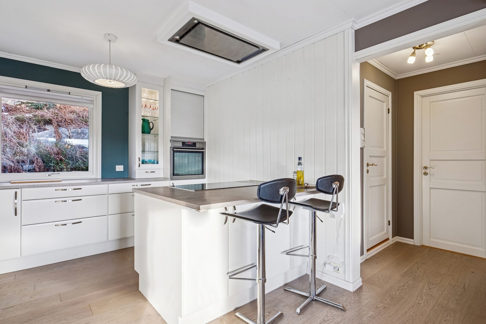 Flott kjøkken med kjøkkenøy og takmontert ventilasjon Galleribilde