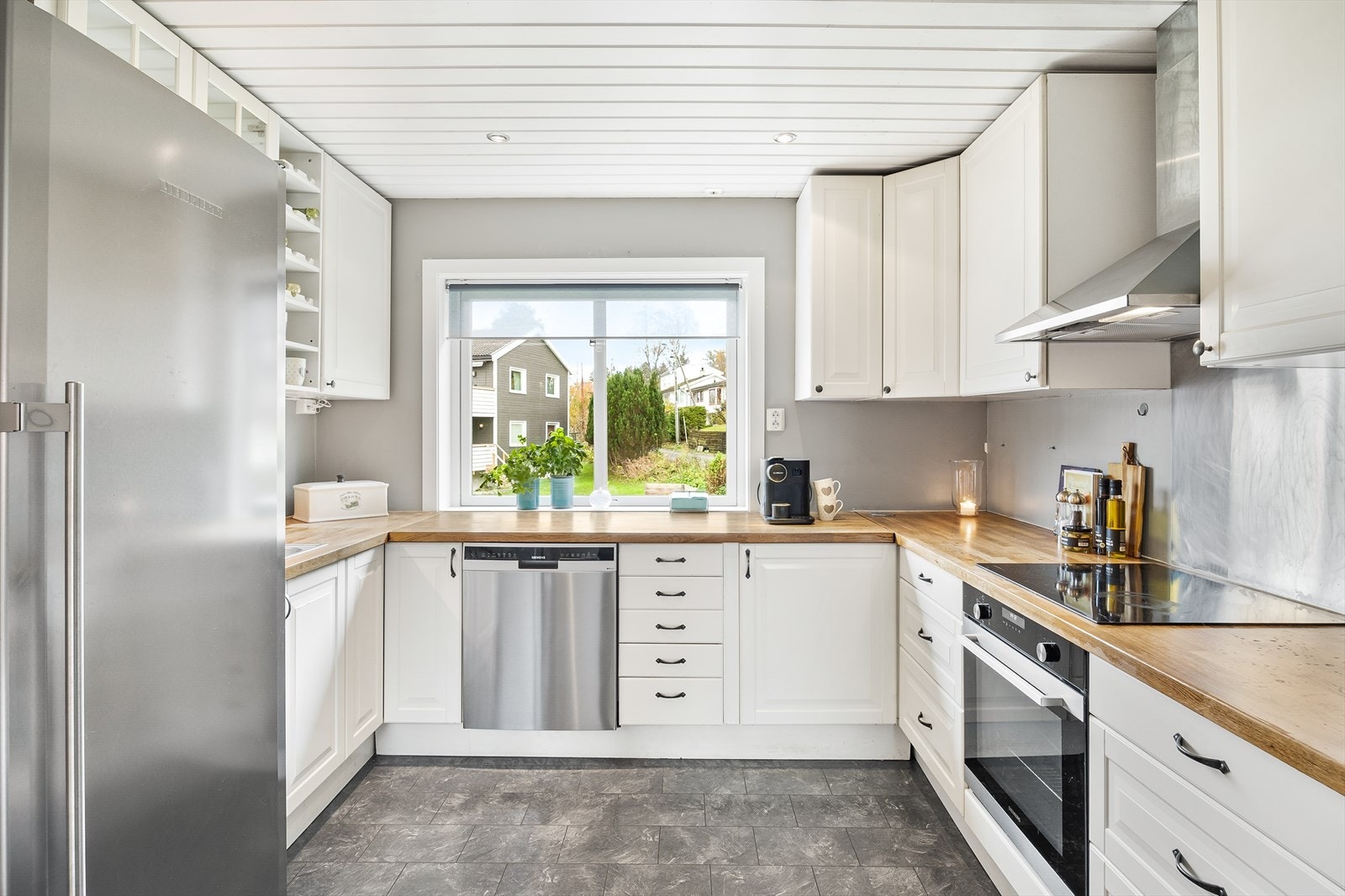 Funksjonelt kjøkken med profilerte fronter, integrerte hvitevarer og en solid benkeplate i heltre. Galleribilde