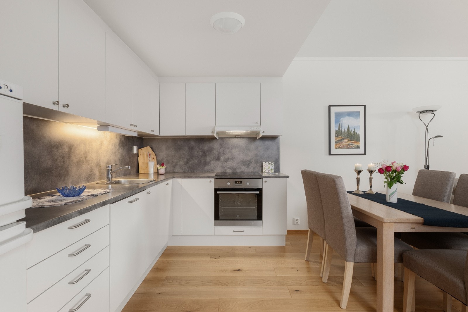 Lys, tidløs innredning med laminerte skrog, glatte fronter og laminert benkeplate med nedfelt stålvask og ettgrepsarmatur. Galleribilde