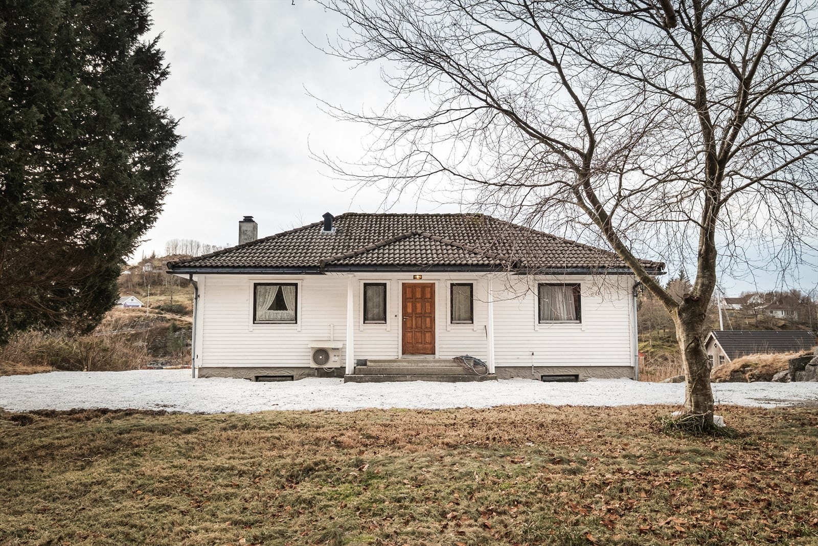 Tomten er opparbeidet rundt huset med plen, forstøtningsmurer og biloppstillingsplasser Galleribilde