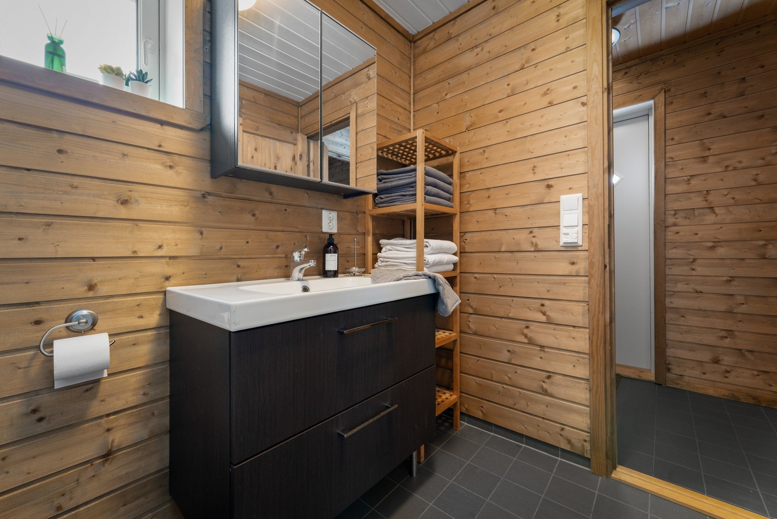 - Det er innredet med håndvask med underskap og speilskap, dusjhjørne med foldedører og gulvmontert toalett - Galleribilde