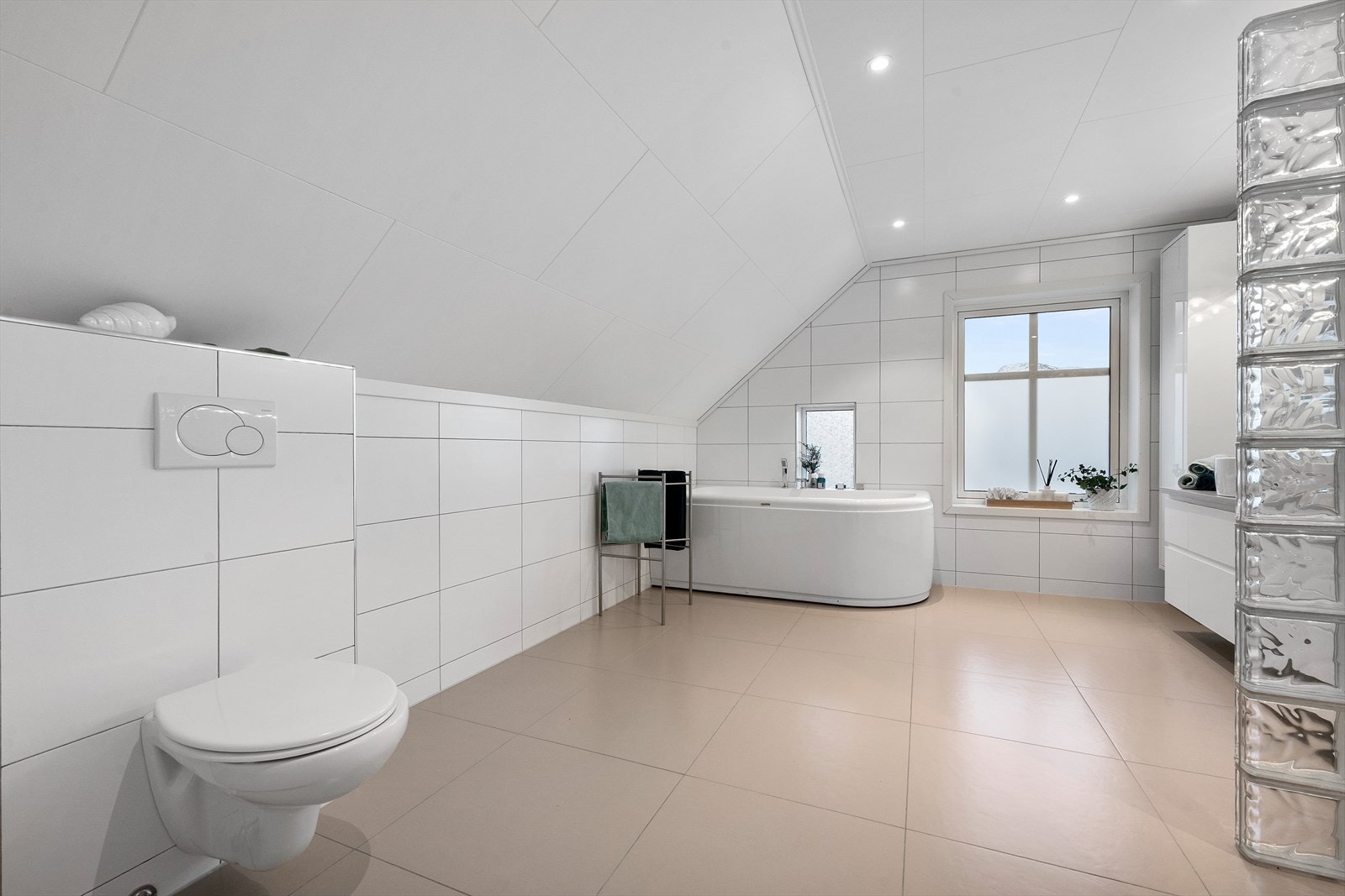 Badet i loftsetasjen har flislagte overflater med vannbåren gulvvarme og spotbelysning i taket. Galleribilde