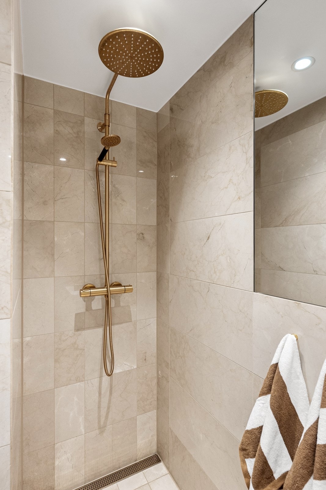 Innredningen består av servant på benkeseksjon med underskap, speil, vegghengt toalett og regnfallsdusj i nisje. Galleribilde