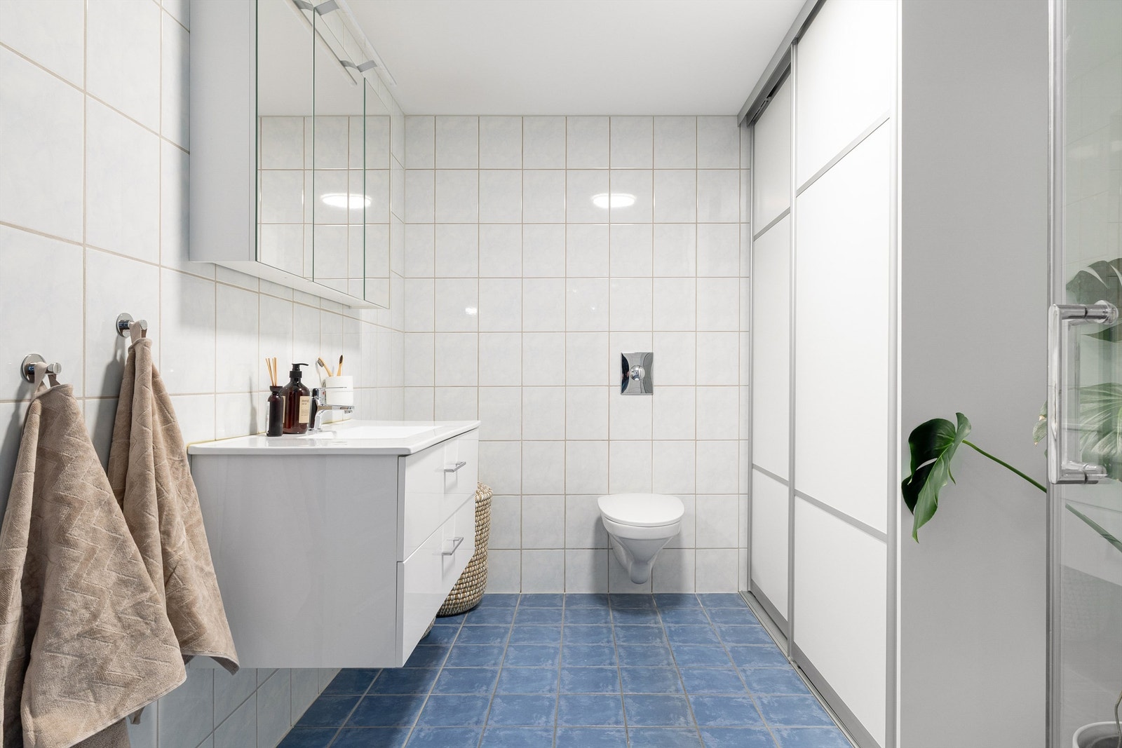 Badet har vegghengt toalett med skyvedører til vask og tørketrommel. Baderomsinnredning fra 2022. Galleribilde