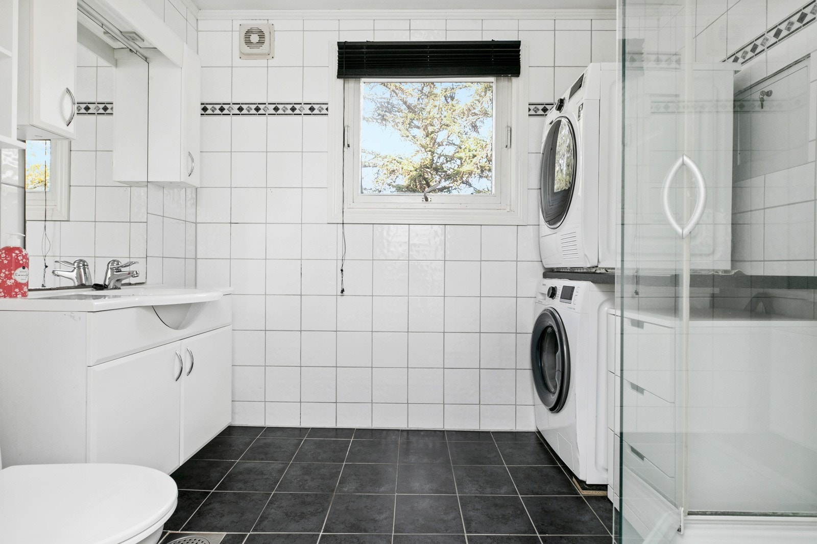 Flislagt bad med varmekabler i 2. etasje. Det er utstyrt med servantinnredning, toalett, dusjkabinett og opplegg for vaskemaskin Galleribilde