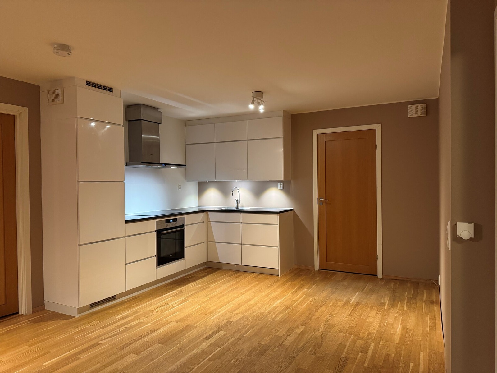 Flott kjøkken i L-form med integrerte hvitevarer. Galleribilde