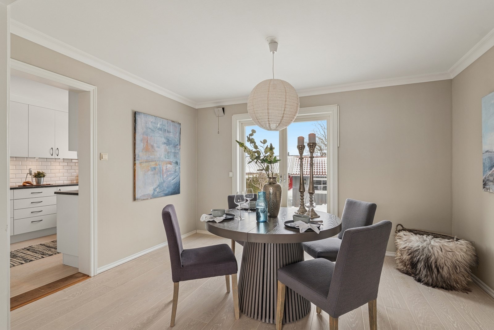 Den tilstøtende spisestuen danner et naturlig midtpunkt i etasjen, og store vindusflater slipper inn rikelig med dagslys samtidig som de rammer inn utsyn mot hagen og det grønne rundt eiendommen. Galleribilde