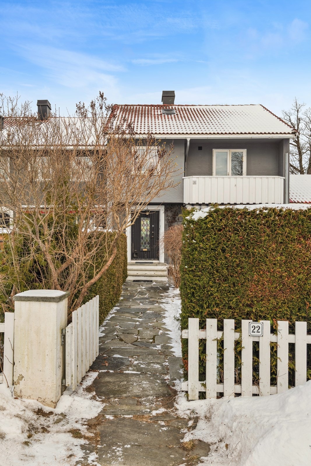 Inngangspartiet fremstår både innbydende og praktisk, med hellelagt adkomst og noen trappetrinn som leder opp til boligens hovedinngang. Galleribilde