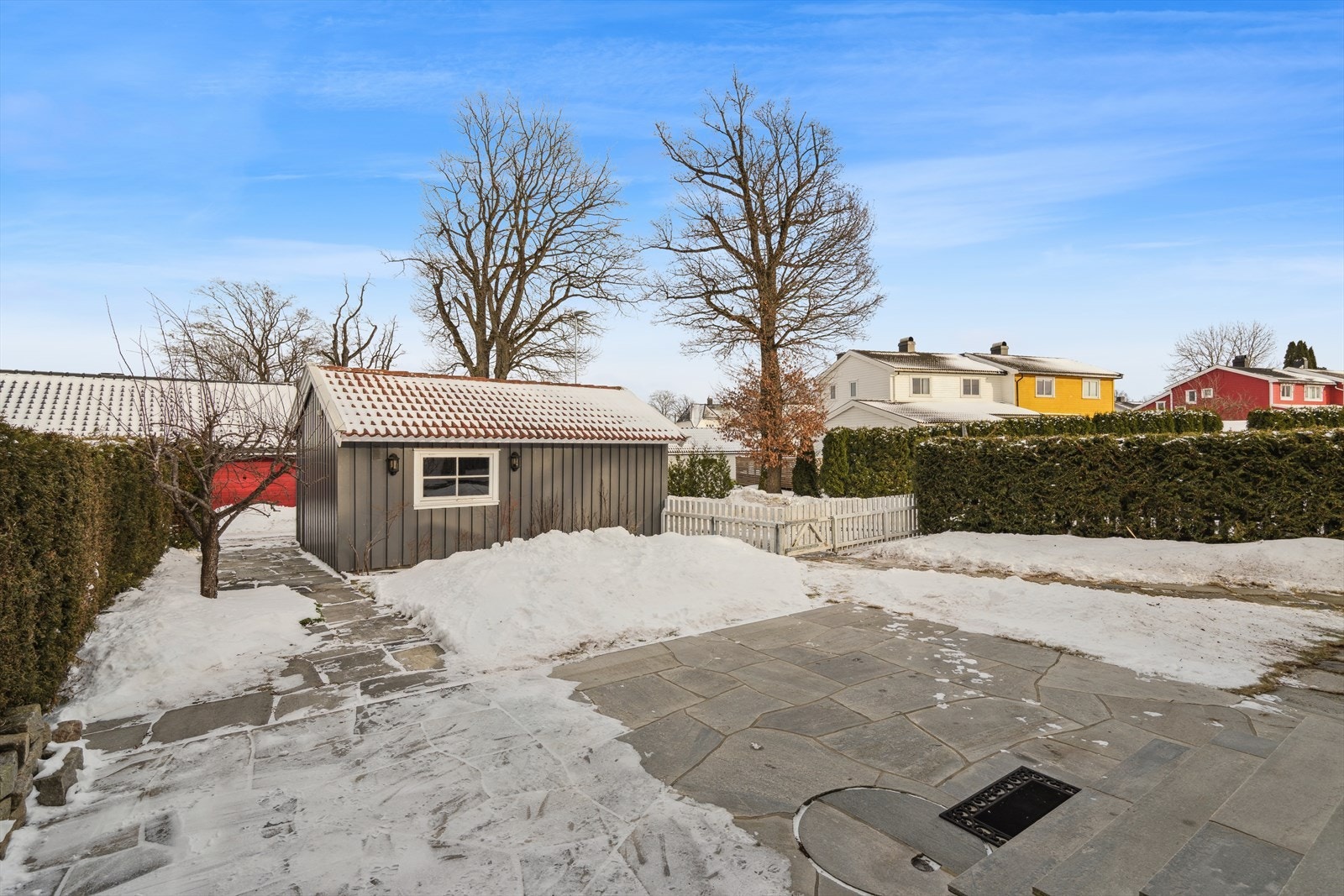 Det er anlagt flott uteplass mot øst hvor det er anlagt hellelagt skiferplatting fra murmester hvor en kommer direkte ut fra spisestuen. Port i gjerde fra denne siden direkte ut til garasjen som står på egen festet tomt. Galleribilde