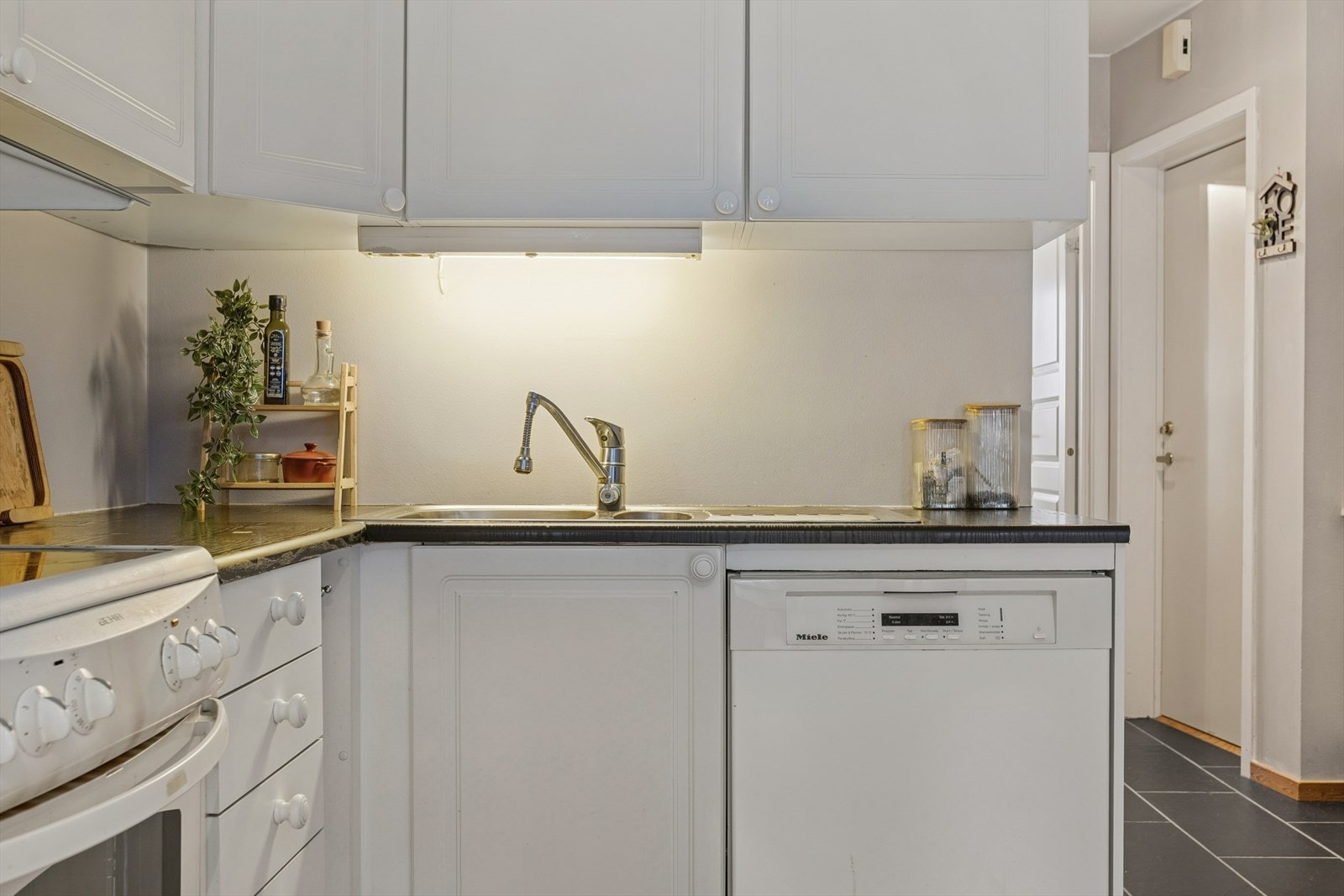 Kjøkkenet er en praktisk og innbydende del av boligen, utformet som en åpen løsning mot stuen som gir en god romfølelse og gjør det enkelt å være sosial mens maten tilberedes. Galleribilde