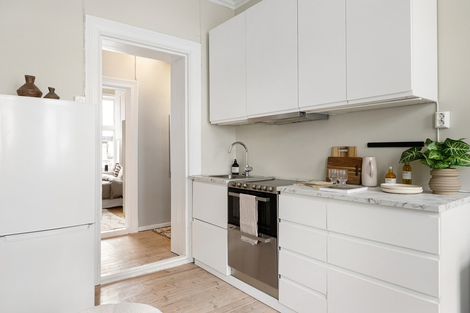 plassert i åpen løsning mot stuen og fremstår moderne og funksjonelt. Innredningen er fra IKEA med glatte fronter, laminat benkeplate og nedfelt oppvaskkum. Kjøkkenet ble flyttet og remontert i 2022, samtidig som det ble montert ny benkeplate. Galleribilde