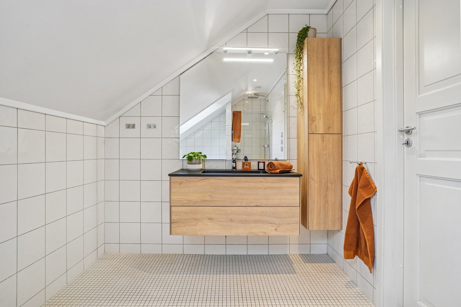 Badet er helfliset med elektriske varmekabler i gulvet. Lekker servantinnredning med glatte skuffefronter og speil med belysning over. Høyskap for god oppbevaring. Galleribilde