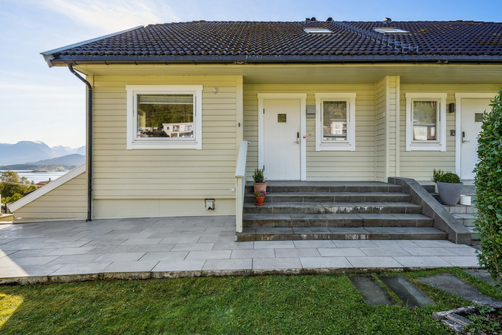 Pent opparbeidet inngangsparti med fliset og hellelagt dekke fra 2024 og trappetilkomst. Galleribilde