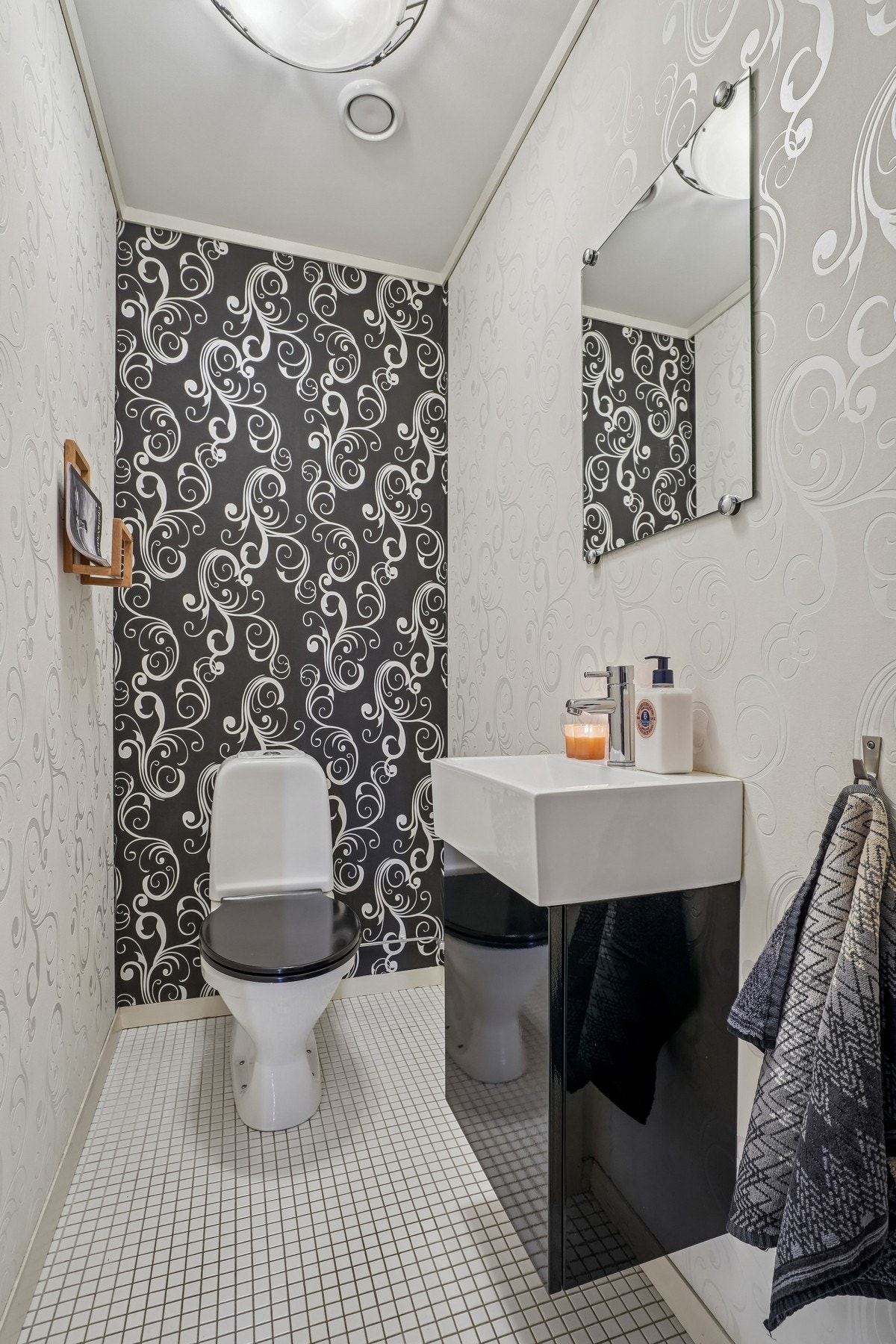 Toalettrommet har fliser på gulvet og tapet på veggene. Galleribilde