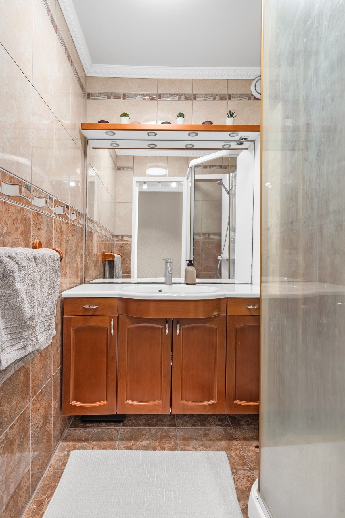 Praktisk baderomsløsning med dusjkabinett og tilrettelegging for vaskemaskin. Heldekkende fliser gir et solid preg og gjør rommet enkelt å vedlikeholde. Galleribilde