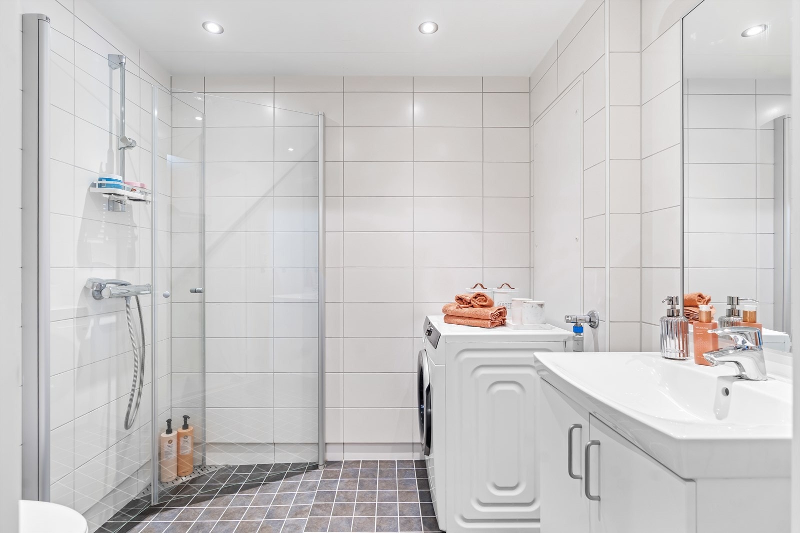 Badet er delikat innredet med mørke gulvfliser, hvite veggfliser, gulvvarme og downlights. Galleribilde