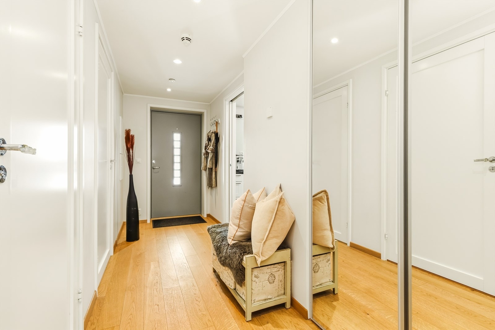 Fra den kombinerte entrèen og gangen ledes man inn til kjøkkenet via skyvedør og til stuen via klassisk sidehengslet dør. Rommet oppleves som lyst og innbydende. Skyvedørsgarderoben (to-dørs) rommer rikelig med oppbevaringsplass for ytterklær og skotøy. Galleribilde