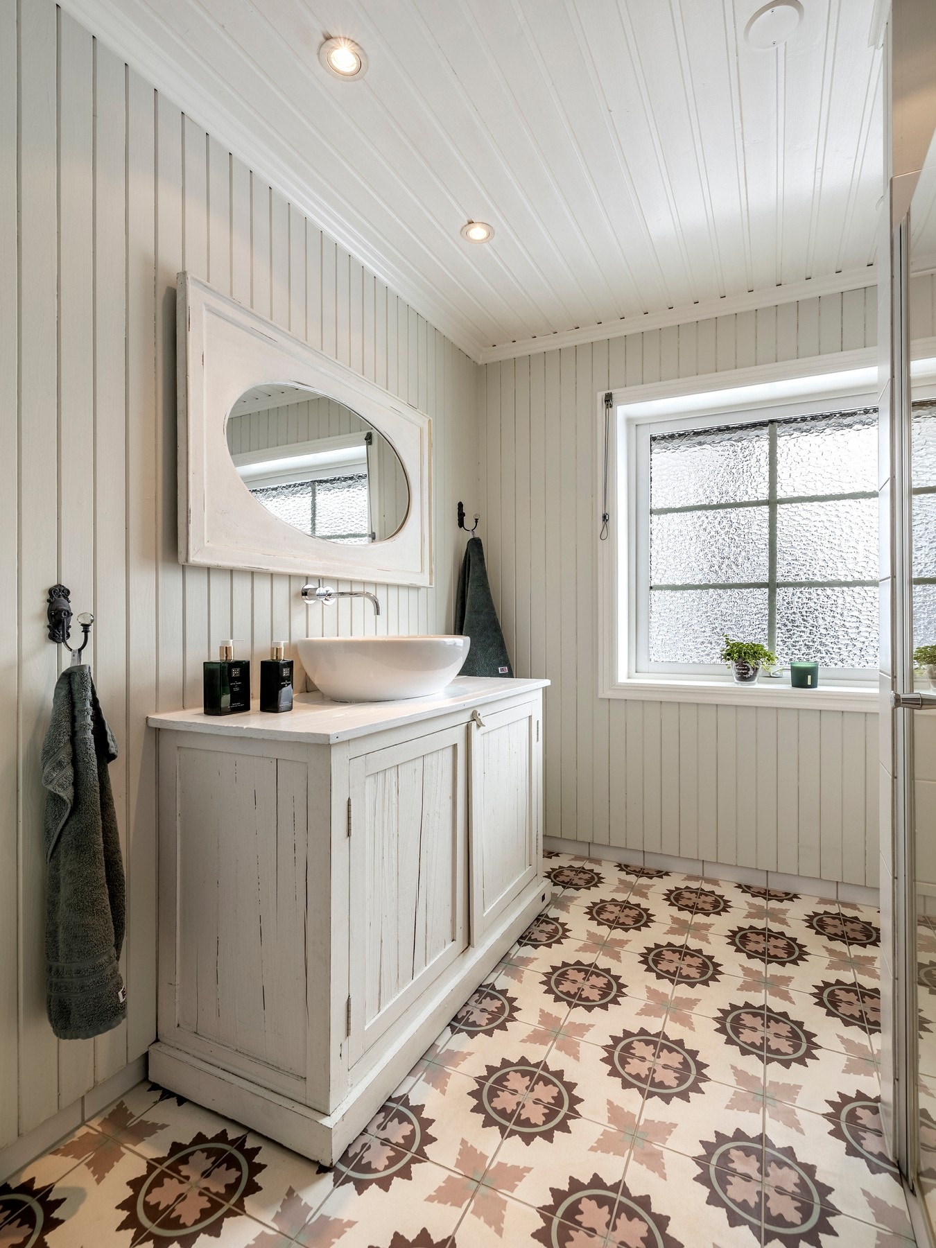 Badet har downlights, flislagt gulv og vegger med trepanel, kombinert med fliser i dusjsonen. Galleribilde