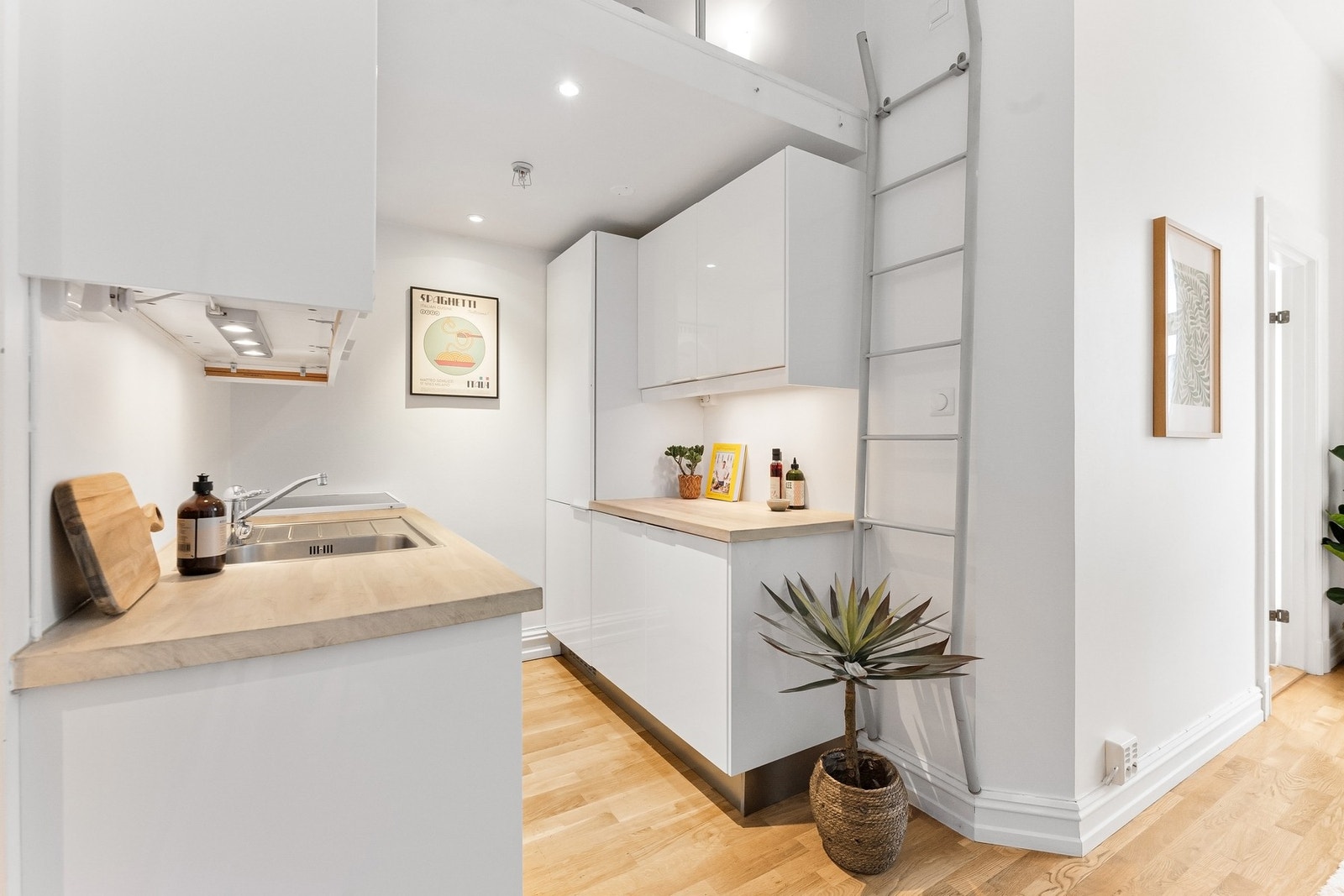 Kjøkkenet er utstyrt med hvite høyglansfronter, benkeplate i massivt tre og integrerte hvitevarer. Galleribilde