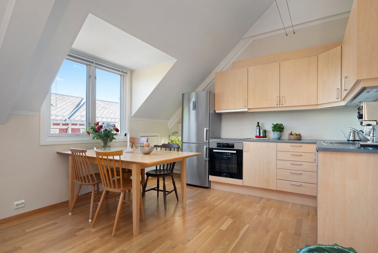 Her får du et praktisk L-formet kjøkken som byr på rikelig med oppbevaringsplass i både over- og underskap, samt godt med benkeplass. Galleribilde