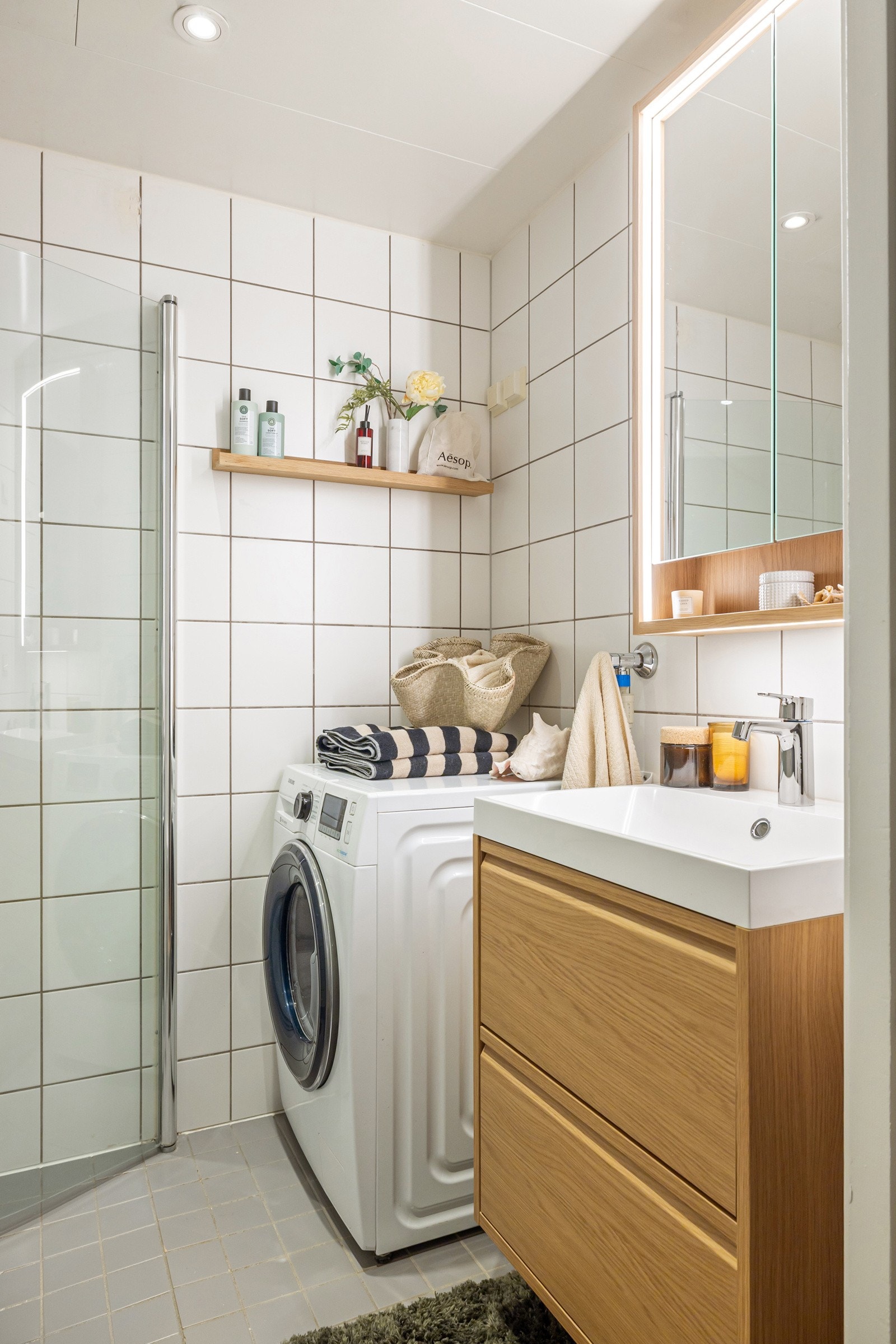 Flott baderomsinnredning fra 2026 med skuffer og ovenpåliggende servant, samt vegghengt speilskap med integrert belysning over. Galleribilde