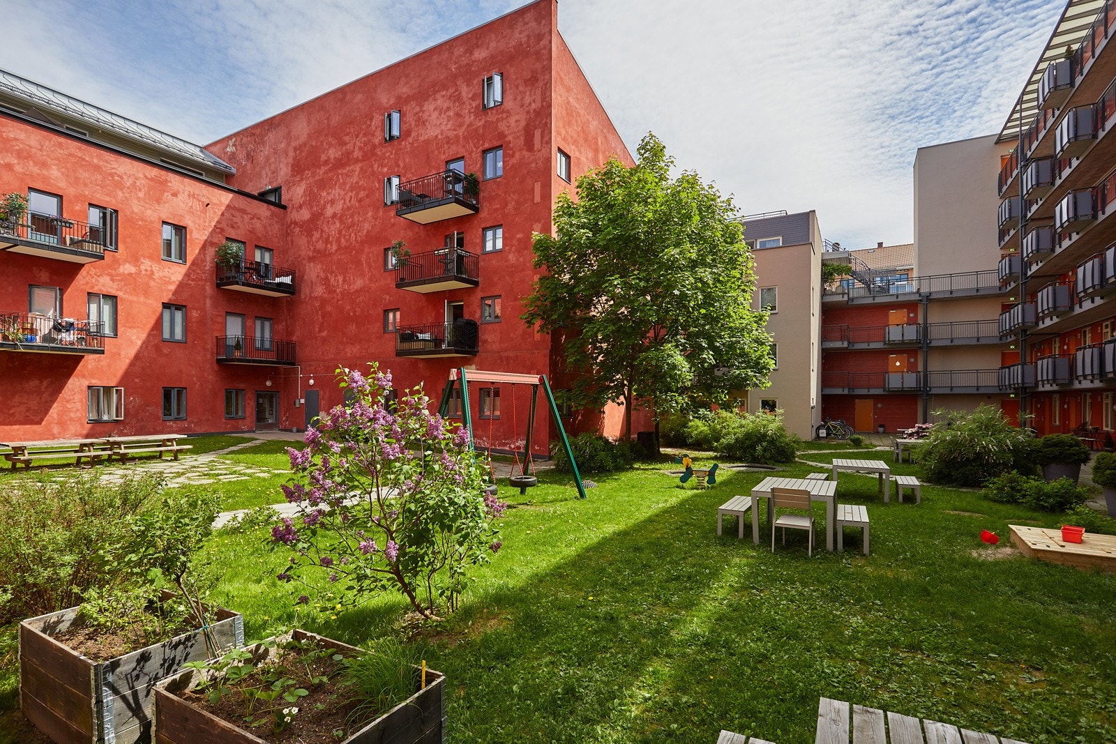 Felles tomt opparbeidet med blant annet asfalterte veier, belegningsstein, sittegrupper, og andre forskjellige beplantninger (arkivbilde). Galleribilde