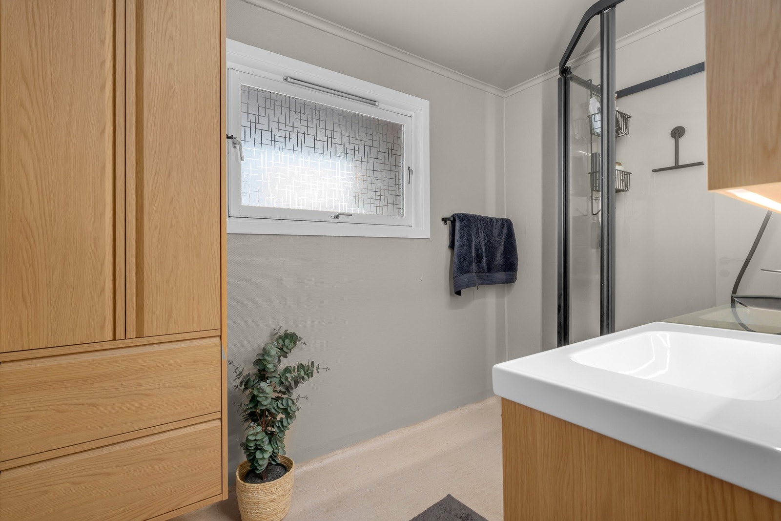 Bad med dusjkabinett, pen baderomsinnredning og praktisk oppbevaring Galleribilde