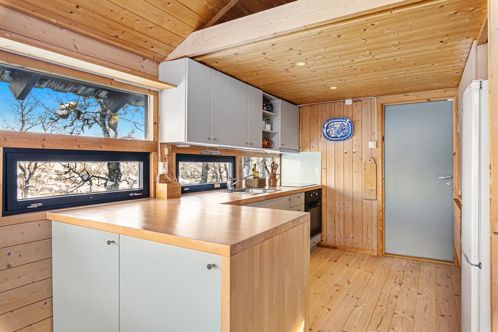 Flott kjøkkeninnredning med slette fronter og benkeplate i heltre Galleribilde