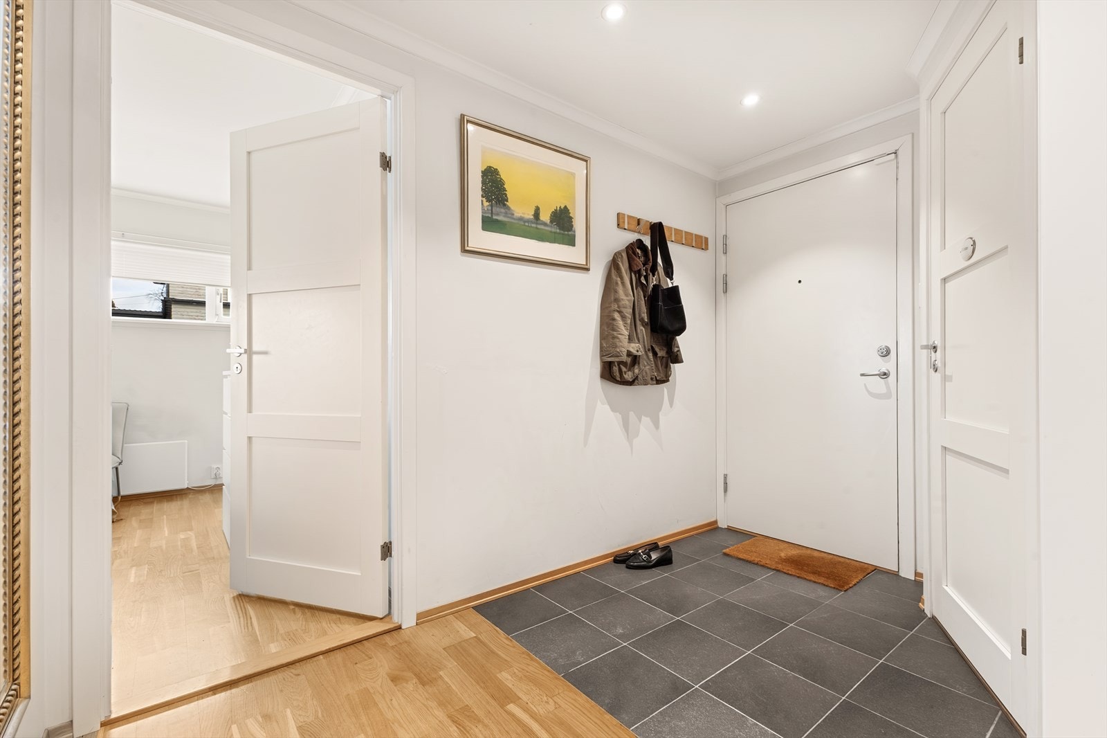 Romslig entré med flislagt gulv og elektriske varmekabler, noe som gir et praktisk og behagelig førsteinntrykk. Entréen fungerer som et naturlig bindeledd mellom boligens ulike soner. Galleribilde