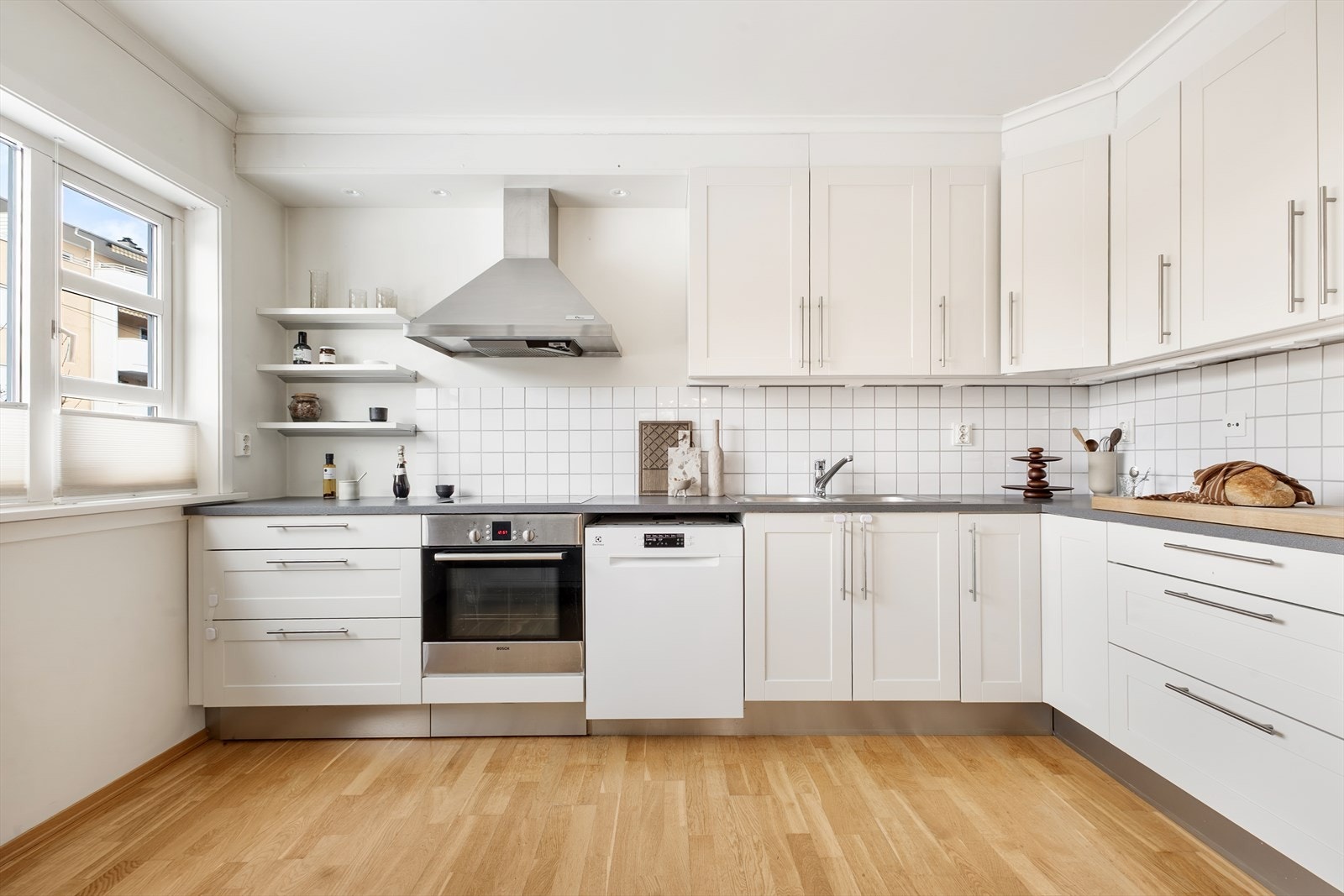 Kjøkkenet ligger i tilknytning til spisestuen og har innredning fra HTH fra byggeår med profilerte, malte fronter og laminat benkeplate. Det er fliser over benk og belysning under overskap. Galleribilde