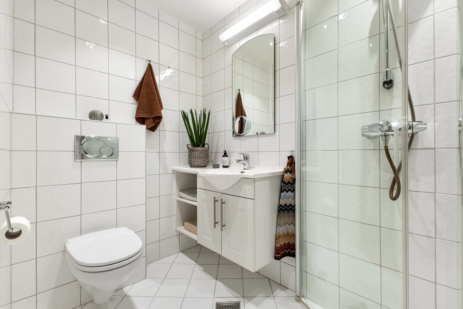 Gjestebadet ligger ved entréen og er innredet med servant, veggmontert toalett og dusjløsning. Galleribilde