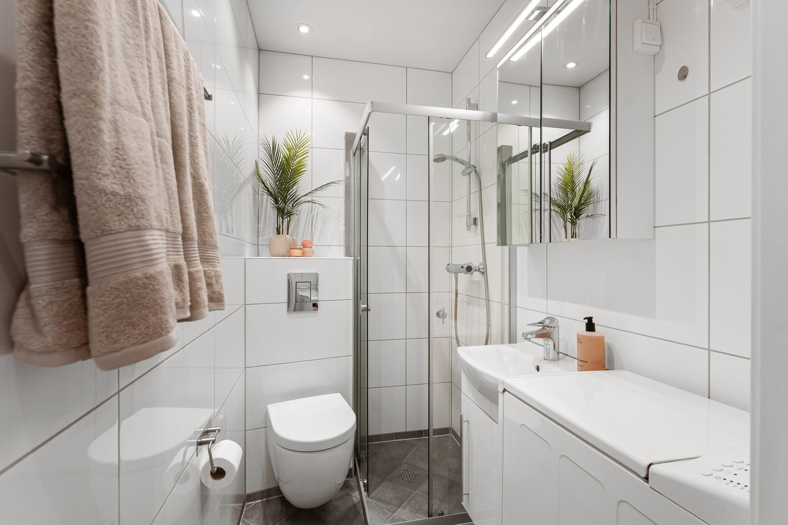 Lyst og pent baderom med gulvvarme og opplegg for vaskemaskin. Galleribilde