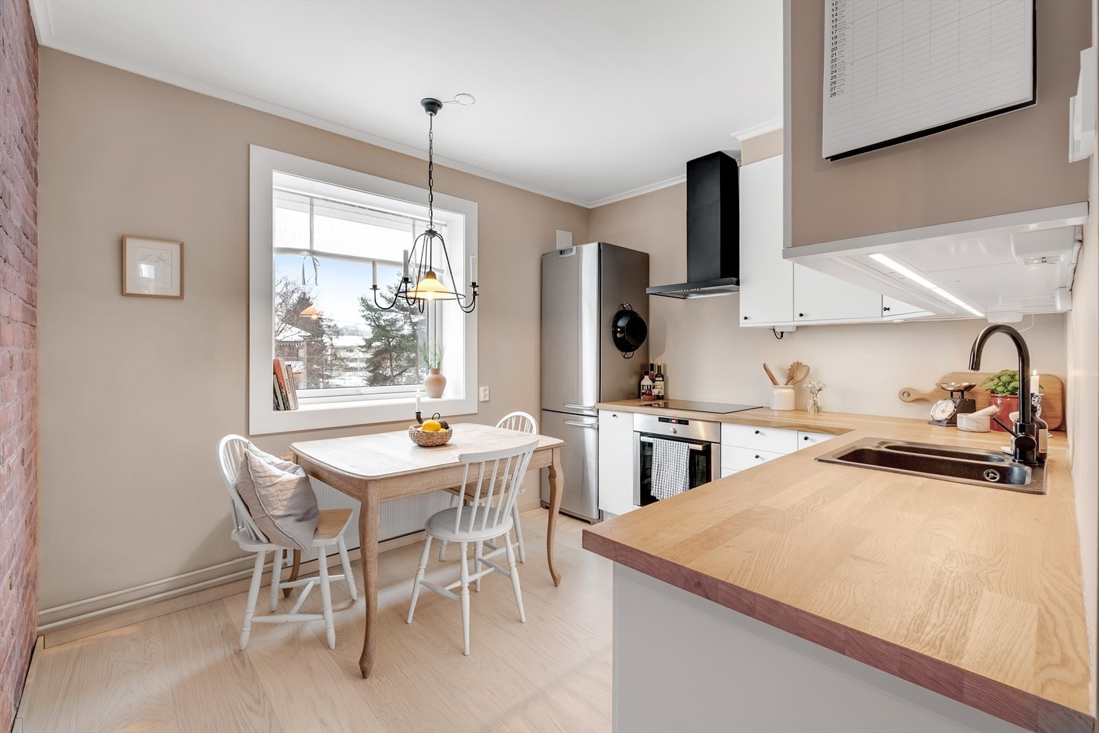 Leiligheten har et separat kjøkken med spiseplass og en karakteristisk teglsteinsvegg. Galleribilde