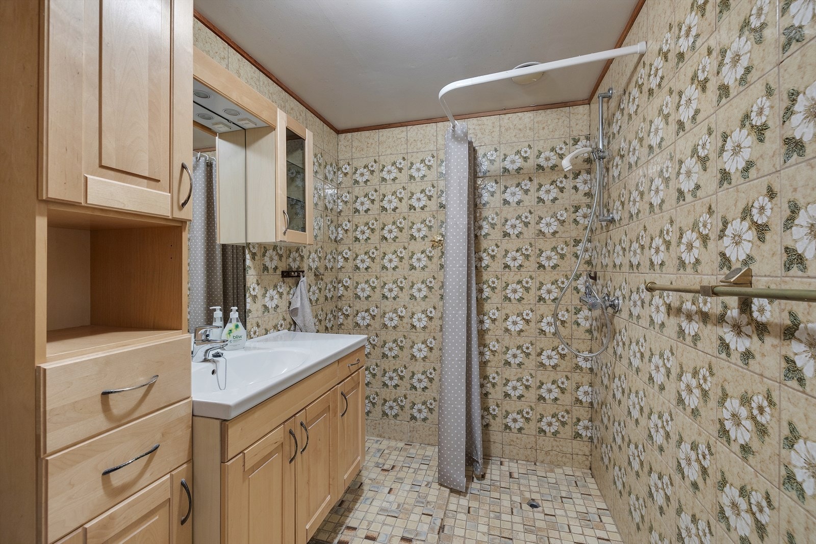 Dusjområdet er avgrenset med dusjforheng, og det er installert hånddusj på veggen. Galleribilde