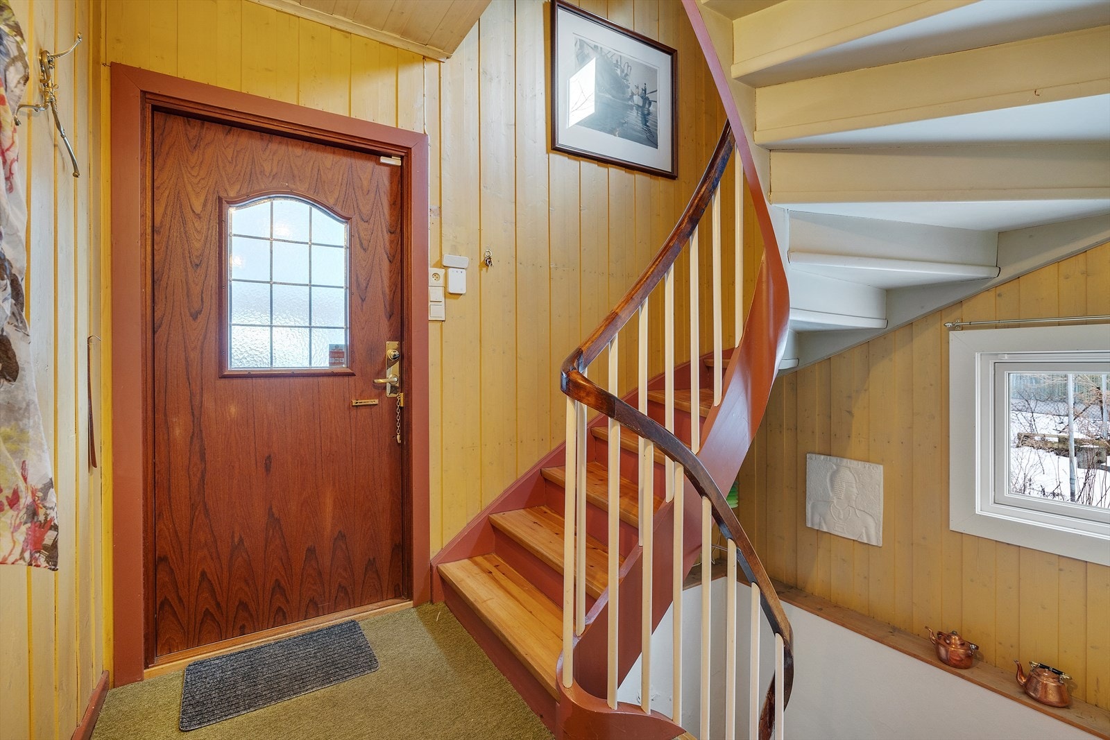 Innvendig trapp med tretrinn og rekkverk i tre gir enkel tilgang til andre etasje og kjeller. Ytterdør med blyglassdetaljer tilfører karakter til inngangspartiet. Galleribilde
