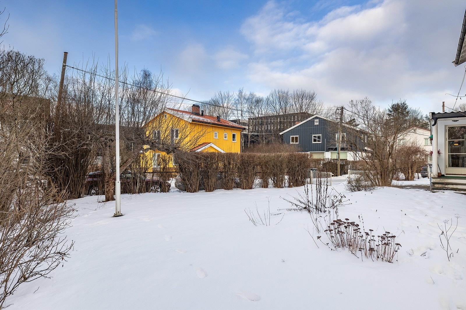 Tomten har en flaggstang og busker langs grensen. Galleribilde
