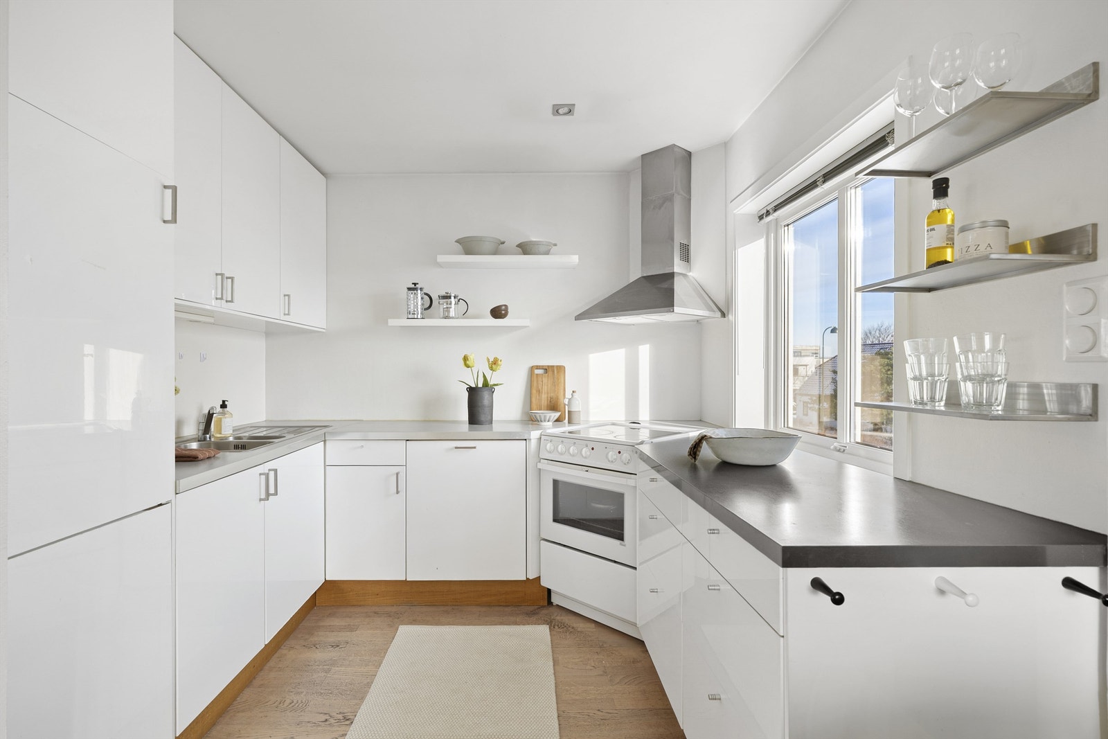 Flott kjøkken med hvite, slette fronter og god skap- og benkplass. Galleribilde