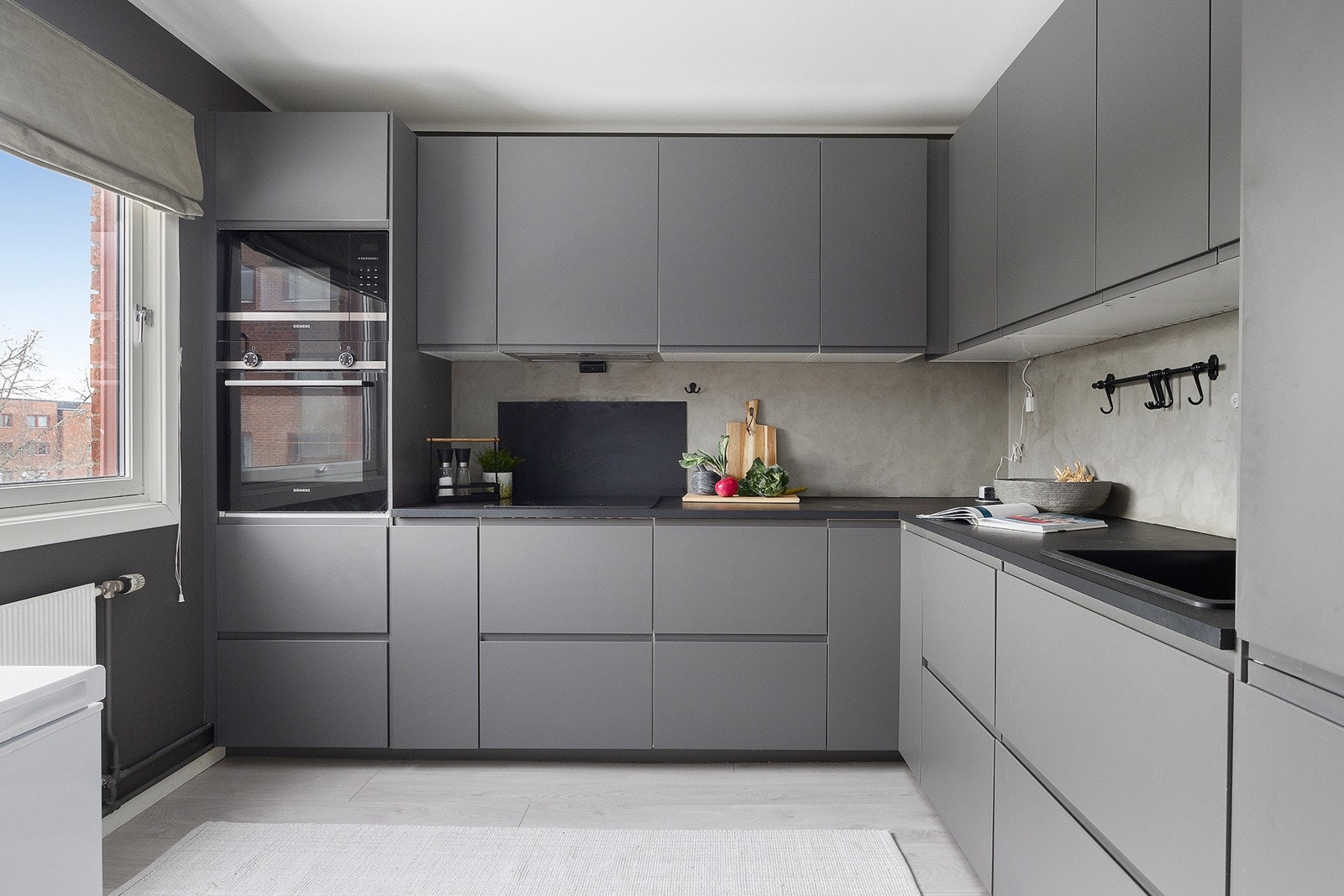 Stilfullt og moderne kjøkken med mørke flater i tilknytning til stue. Galleribilde