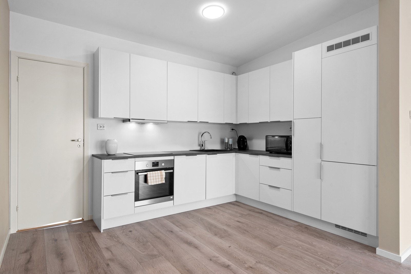 Tidløst og plassutnyttet kjøkken med integrerte hvitevarer godt plassert for en smidig tid på kjøkkenet. Galleribilde