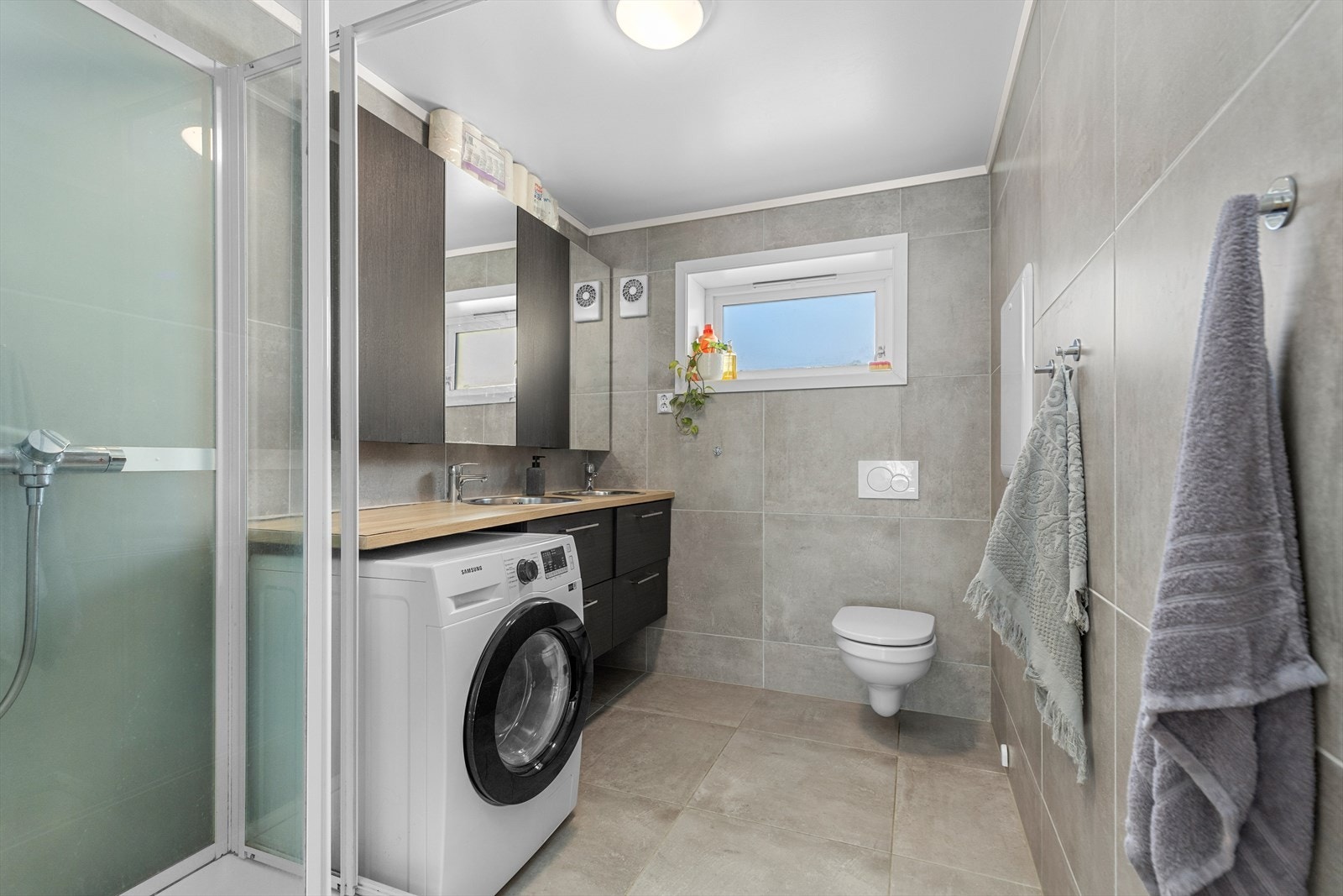 Badet er som i likhet med badet i 1. etg oppgradert i 2018 med flislagt gulv og behagelig gulvvarme. Det er utstyrt med veggmontert wc, servantskap og servant, opplegg for vaskemaskin, dusjkabinett, mekanisk avtrekk og rørfordelingsskap. Galleribilde