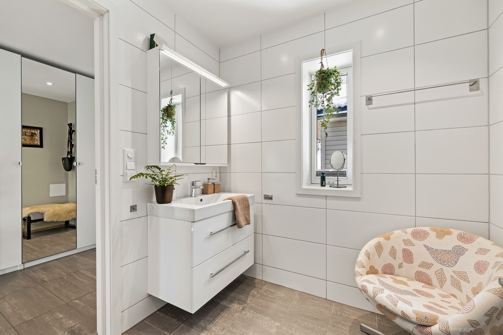 Tidsriktig utført bad innredet med vegghengt toalett, heldekkende servant med oppbevaring i skuffer. Speilskap med belysning som skaper en fint lys på badet. Galleribilde