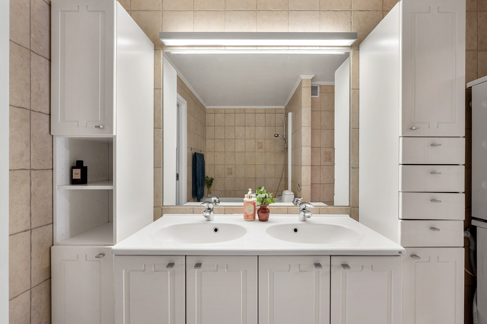 Flislagt baderom med oppbevaring i skuffer og skap. Det er montert varmekabler i gulv Galleribilde