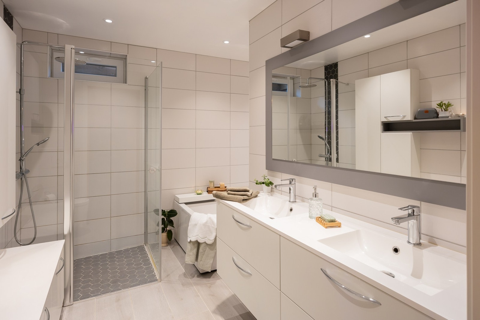 Her finner du både dusjløsning med glassvegger, badekar, vegghengt toalett og pen baderomsinnredning. Galleribilde