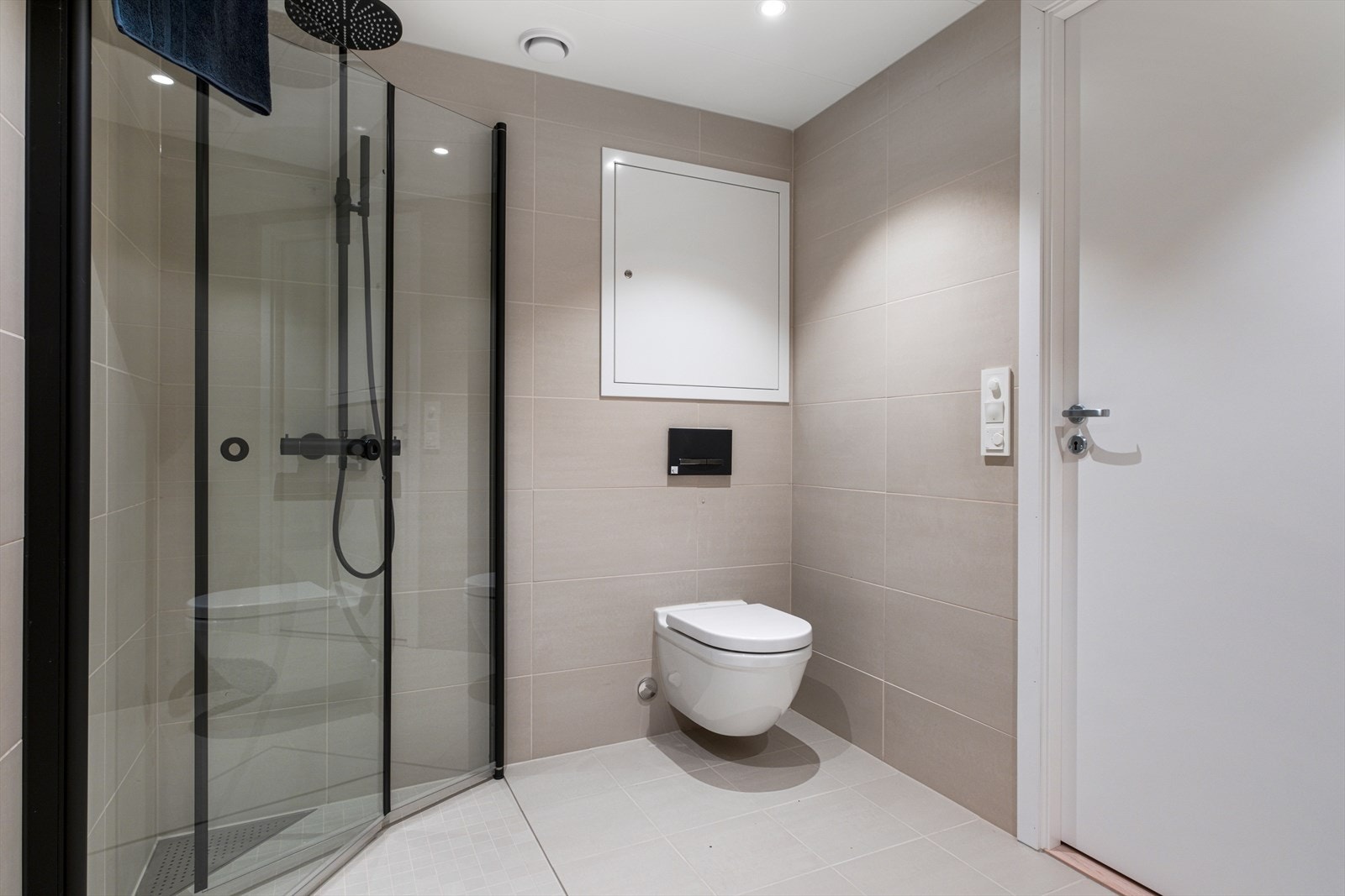 Det er innredet med praktiske innfellbare dusjdører i dusjhjørne, baderomsinnredning med speilskap og dobbelservant, opplegg for vaskemaskin, veggmontert wc og downlights Galleribilde