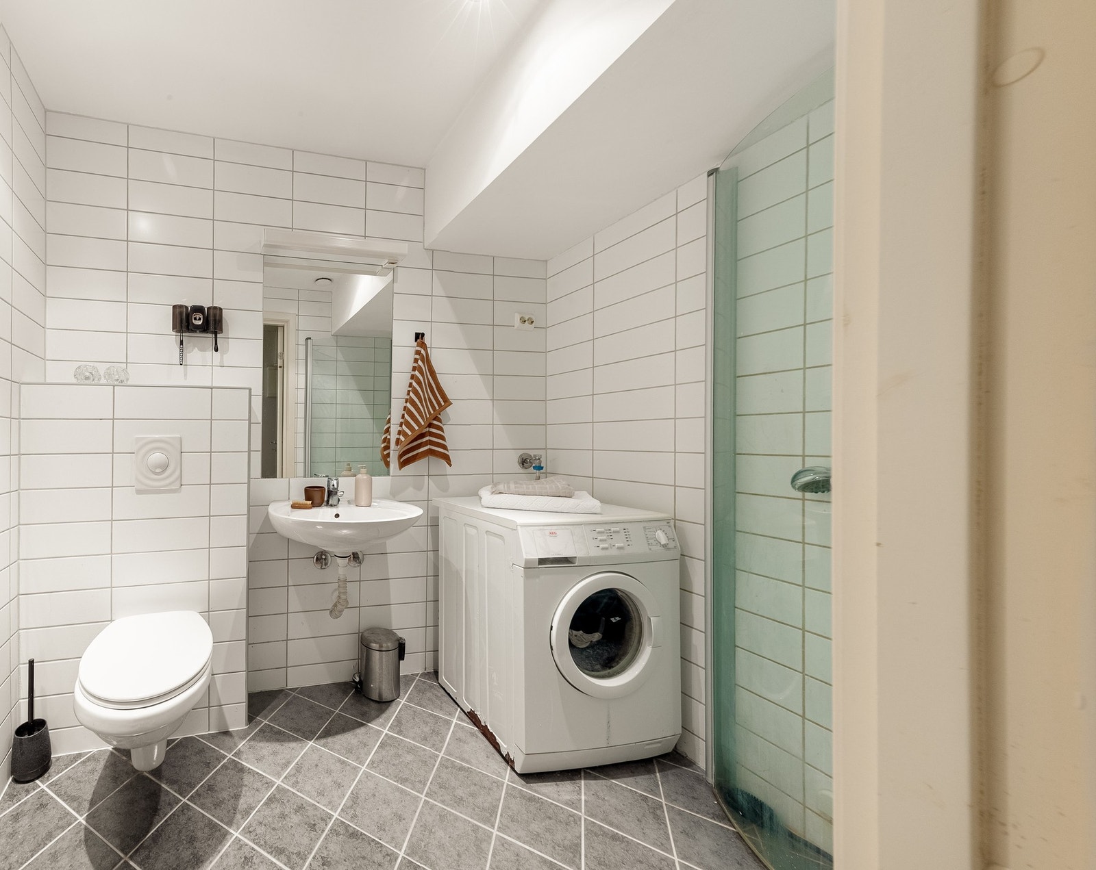 Romslig baderom med vegghengt toalett, dusjhjørne, servant og opplegg for vaskemaskin. Bad ble oppusset i 2006. Galleribilde