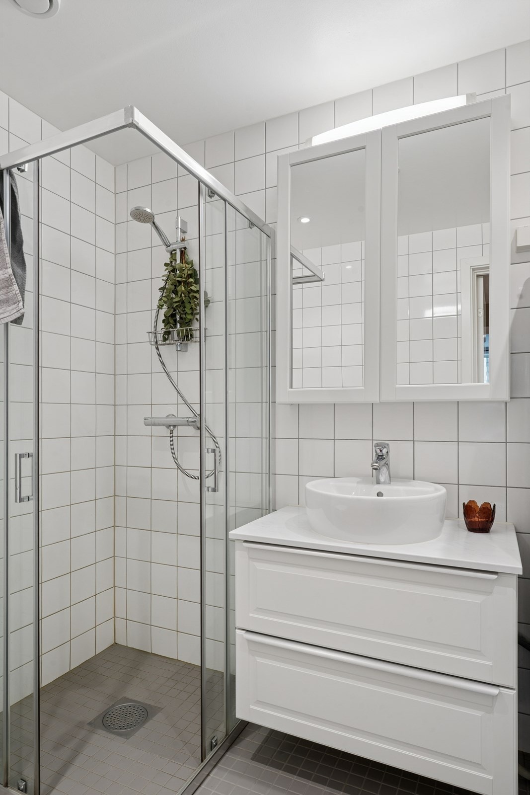 Dusjhjørne med glassvegger og veggmontert toalett med innbygningssisterne. Galleribilde