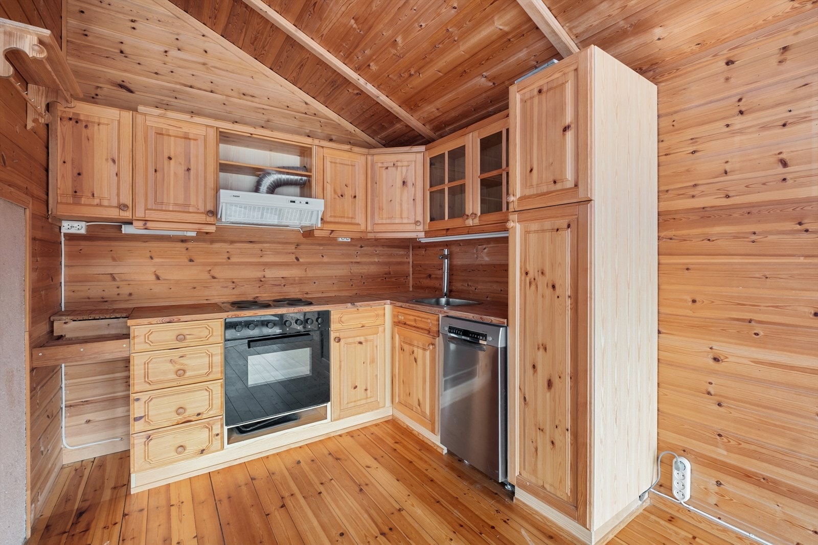 Kjøkkenet har trehvit innredning med integrert komfyr og oppvaskmaskin Galleribilde