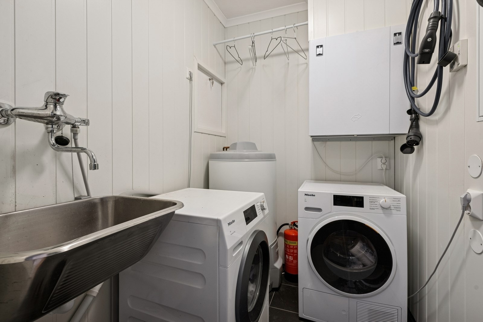 Eget praktisk vaskerom/teknisk rom (godkjent som bod) med flislagt gulv og varmekabler. Rommet er innredet med utslagsvask og opplegg for vaskemaskin. Galleribilde