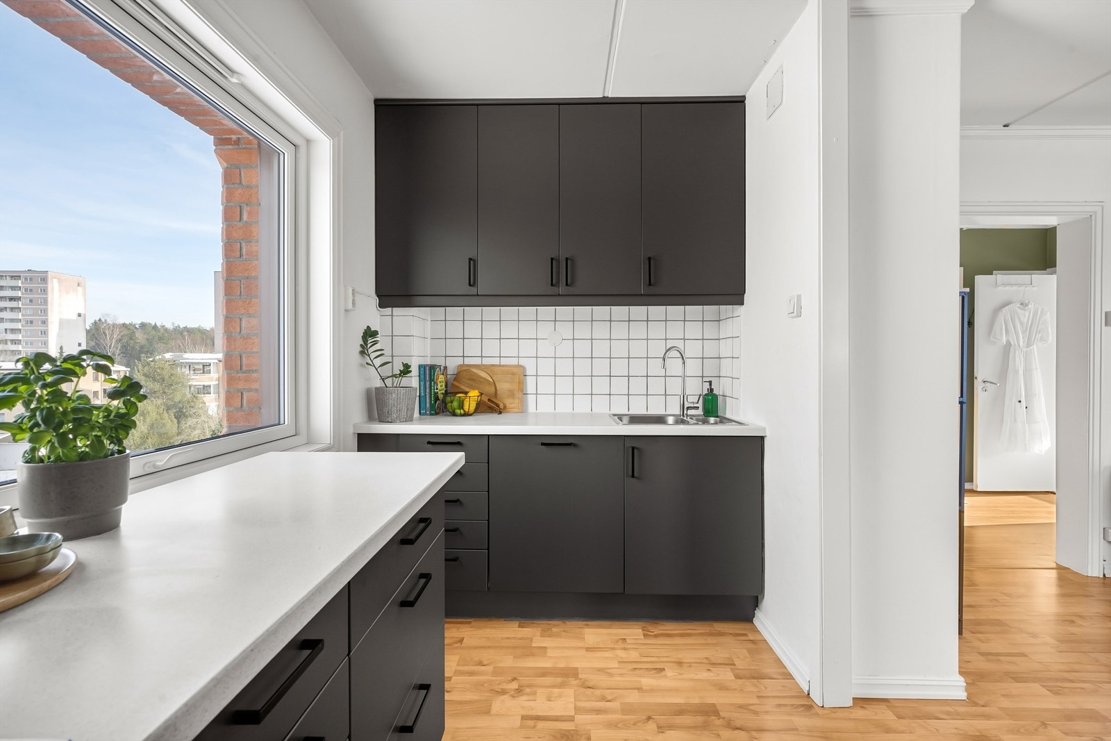 Laminert benkeplate med nedfelt vask og fliser mellom benk og overskap. Galleribilde