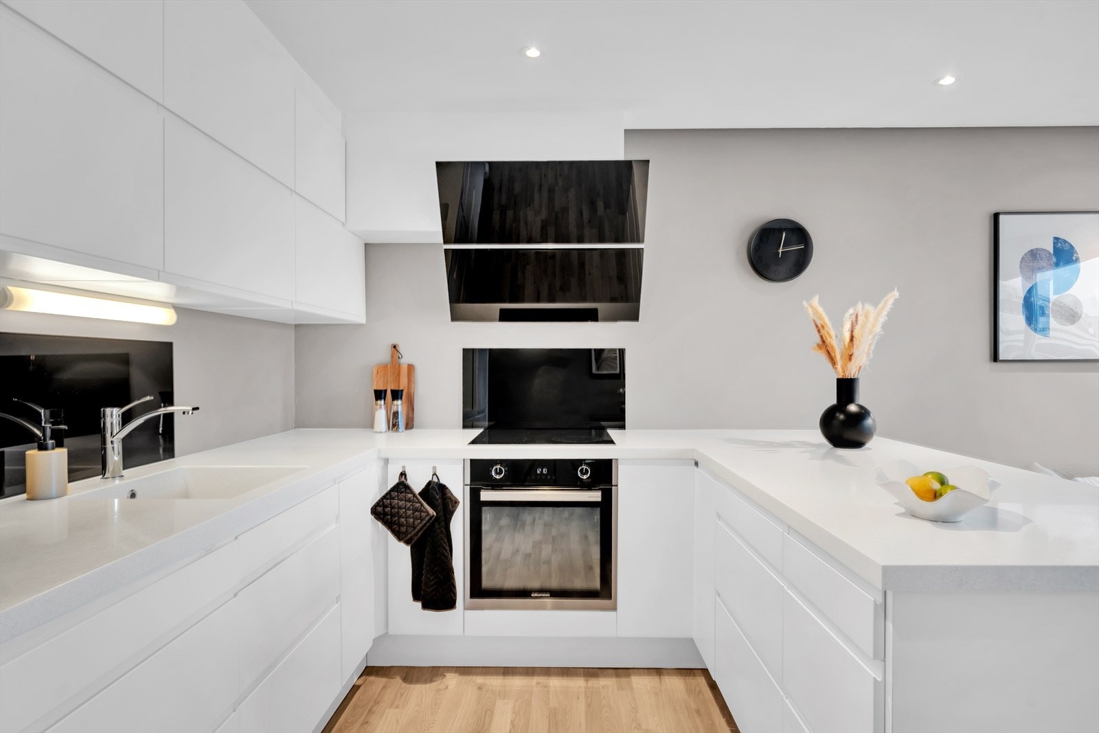 Pent kjøkken med slette fronter og integrerte hvitevarer. Galleribilde